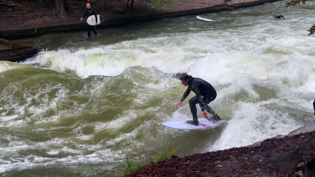 Autumn Fall surfers River Surfing morning Eisbachwelle Eisbach Isar River Munich Germany Englischer Garten artificial standing wave tourist watching attraction action sports stunts air reverse pan