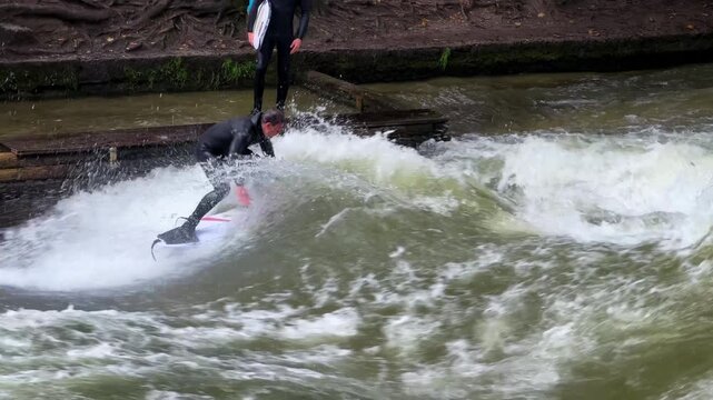 Autumn Fall surfers River Surfing morning Eisbachwelle Eisbach Isar River Munich Germany Englischer Garten artificial standing wave tourist watching attraction action sports stunts air reverse follow
