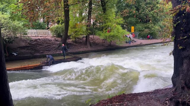Autumn Fall surfers River Surfing morning Eisbachwelle Eisbach Isar River Munich Germany Englischer Garten artificial standing wave tourist watching attraction action sports stunts turning slash