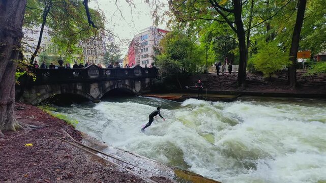 Autumn Fall wet suit surfers River Surfing morning Eisbachwelle Eisbach Isar River Munich Germany Englischer Garten man made standing wave action sports water sports stunts air reverse sections turns
