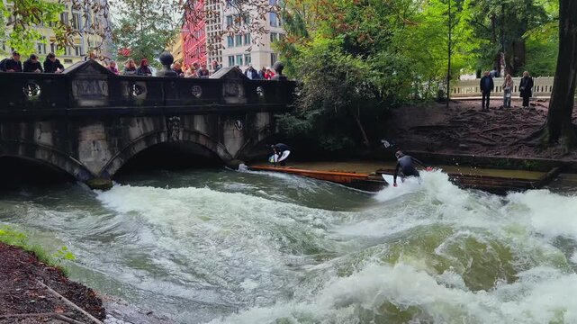 Autumn Fall wet suit surfers River Surfing morning Eisbachwelle Eisbach Isar River Munich Germany Englischer Garten man made standing wave action sports water sports stunts air reverse pan follow