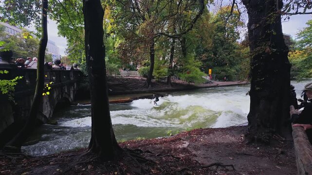 Autumn Fall wet suit surfers River Surfing morning Eisbachwelle Eisbach Isar River Munich Germany bridge view Englischer Garten artificial man made standing wave action sports water sports stunts air