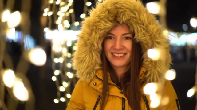 Woman in Yellow Winter Coat Smiling at Christmas Lights.
