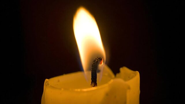 A close-up view of a candle flame. Bright, translucent, fiery, and illuminating the darkness