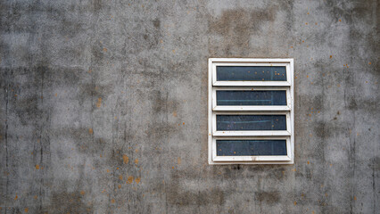 Minimalist exterior concrete wall with a small rectangular window on the right side. Weathered cement texture background with large empty copy space, suitable for web design, banners, posters, and mod