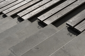 Empty stadium seating with wooden benches and numbered concrete steps
