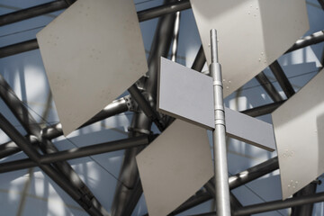 Blank directional street signs on metal pole against modern geometric architecture background