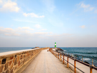 Obraz premium Snowy Pier with Lighthouse in Winter – Rostock-Warnemünde on the Baltic Sea (Germany)