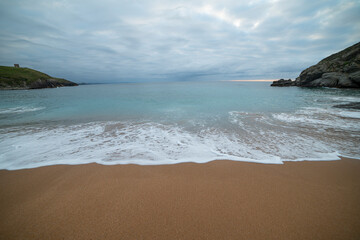 Sandy beach with gentle waves and cloudy sky.. Santander, Spain