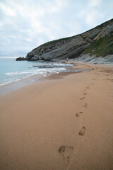 Sandy beach with footprints and rocky cliffs.. Santander, Spain