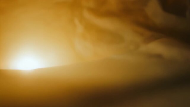 Golden light breaking through dense atmospheric darkness, illuminating a subtle surface below, symbolizing concepts of hope, guidance, and the unknown path ahead