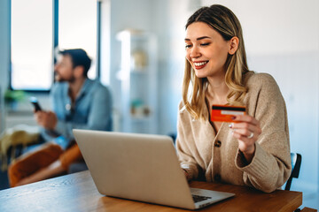 Young woman making an online payment with a credit card and laptop at home, cashless lifestyle
