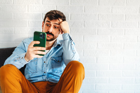 A disappointed man checking his smartphone, online problems, bad news, digital setbacks