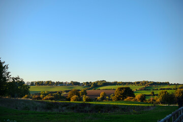 Beautiful rural sunset landscape in the green fields meadows in the Cotswolds, England