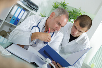 Obraz premium senior and junior male doctors looking at file