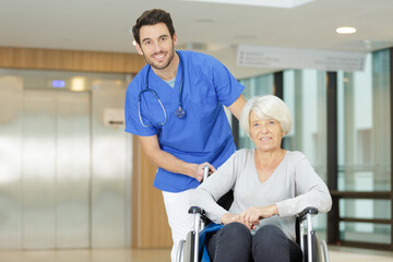 Fototapeta premium nurse pushing senior patient in wheelchair along corridor