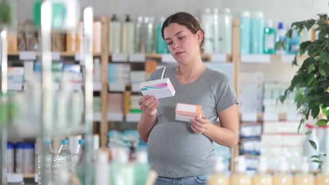 Pregnant woman buys toxicosis pills at a pharmacy. Woman chooses cold pills that can be used by pregnant women. High quality 4k footage