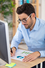 businessman wearing eyeglasses at computer desk working on charts