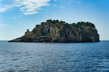 Naklejka premium Dramatic rocky island with distinctive cave opening carved into limestone cliff formation.