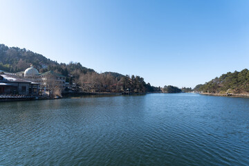 Obraz premium A tranquil lake with a clear blue sky sits in Lushan Mountain, Jiangxi China, surrounded by hills and trees