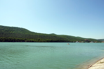 Lake with green hills under sunny sky on summer day