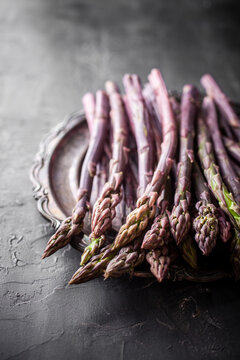 Purple asparagus and gourmet food styling on dark background