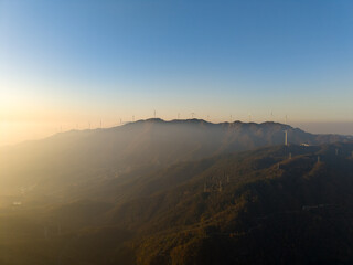 Naklejka premium Wind turbines on a misty mountain range in Wuhan, China during sunrise