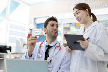 Male and female pharmacists reviewing medication together. Healthcare professionals collaborating...