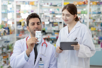 Male and female pharmacists reviewing medication together. Healthcare professionals collaborating...