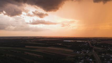 Fototapeta premium Dramatic sunset with heavy clouds over summer fields