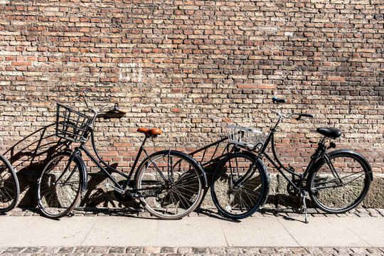 Row of bicycle parking against brick wall on urban street in Copenhagen Denmark showing simple transport routines and daily cycling