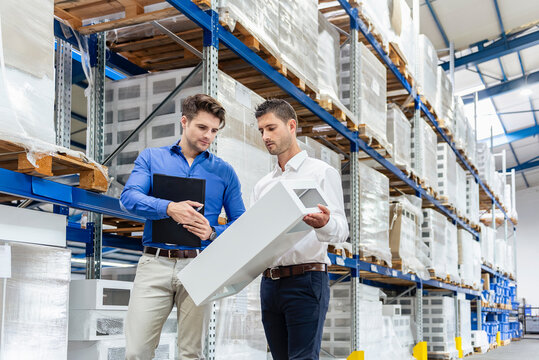 Business meeting in production hall with product sample and clipboard