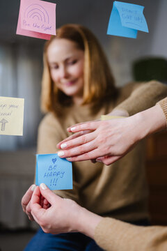 Woman placing affirmations on sticky notes for inspiration and wellness on mirror