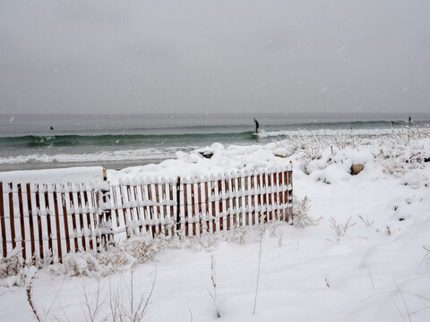 Surfer on a wave in a snowstorm at Higgins Beach