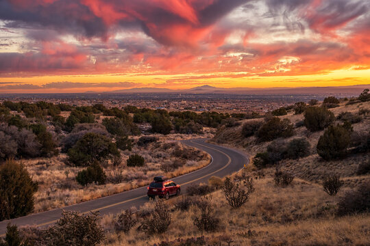 Red Car Driving Into A Vibrant Albuquerque Sunset