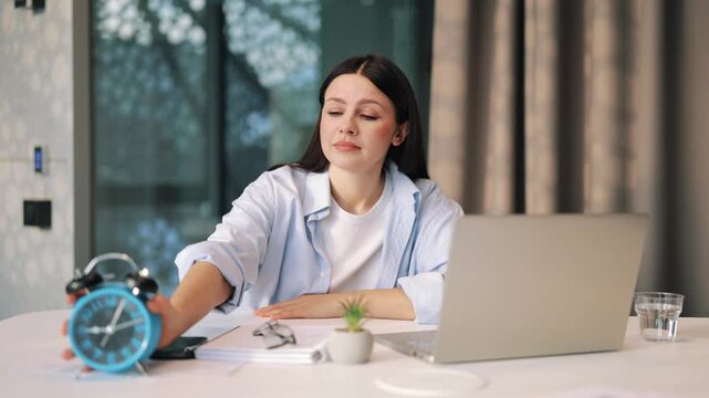 Exhausted woman struggles with time, yawning and eventually falling asleep at office desk. Feeling overwhelmed, this scene captures burnout and the toll of long hours on emotional well-being.