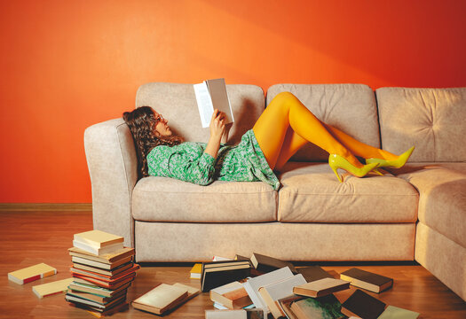 Person relaxing on sofa reading book in bright living room