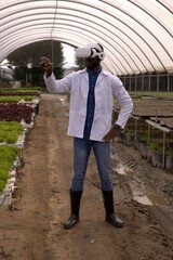 Researcher wearing VR headset is exploring hydroponic lettuce troughs inside hoop-style greenhouse © wavebreak3