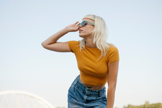 Hipster with sunglasses in casual clothes posing outdoors in urban setting