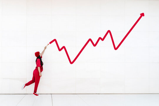 Woman in red drawing upward graph symbolizing business growth