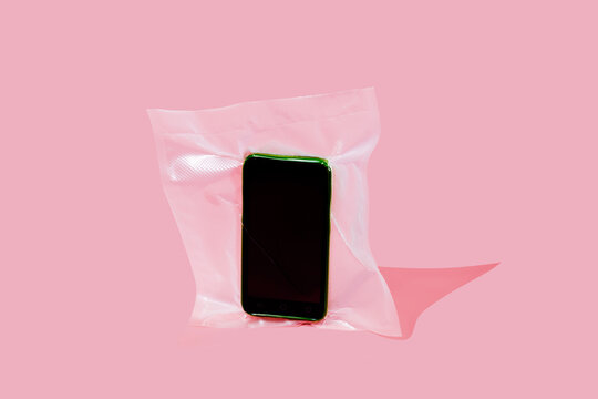 Vacuum sealed smartphone on pink background symbolizing digital detox