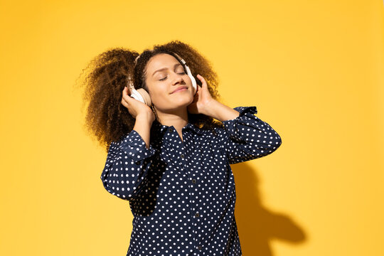 Beautiful woman enjoying music against yellow background