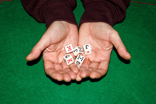 Hands holding dice over green mat during board game leisure activity