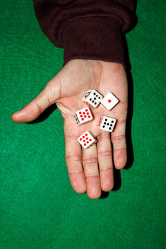 Hand holding assorted dice on green gaming mat closeup