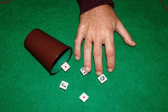 Hand rolling dice on green game mat in leisure and entertainment setting