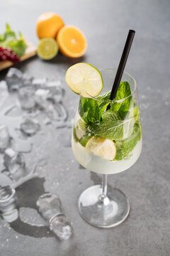 Refreshing Lime Mint Sparkling Water with Ice in Elegant Wine Glass on Gray Background