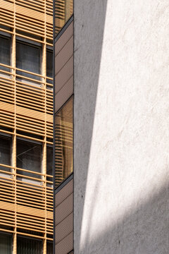 Modern architecture facade with wood louvers and windows casting shadow pattern and geometry for abstract sustainable building exterior detail