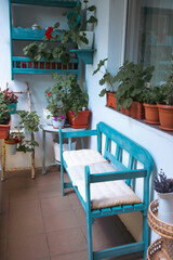 Obraz premium Small balcony with blue wooden bench and summer flowers.