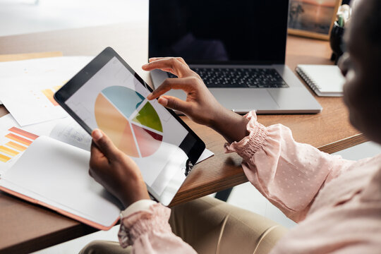 Black woman analyzing financial data on tablet pie chart