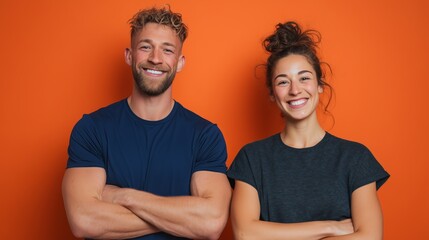 Fototapeta premium Confident couple smiles with arms crossed, standing against a vibrant orange background, exuding positivity and energy.